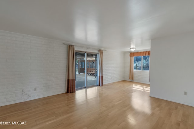 empty room featuring brick wall and light wood-type flooring