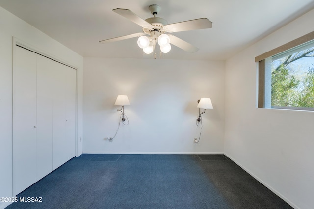 unfurnished bedroom with ceiling fan, a closet, and dark colored carpet