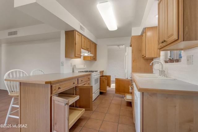 kitchen featuring a kitchen bar, light brown cabinetry, sink, kitchen peninsula, and white appliances