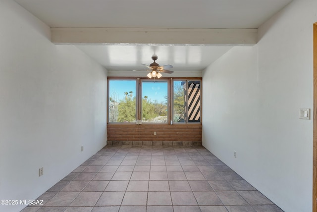 tiled empty room with ceiling fan, brick wall, and beam ceiling