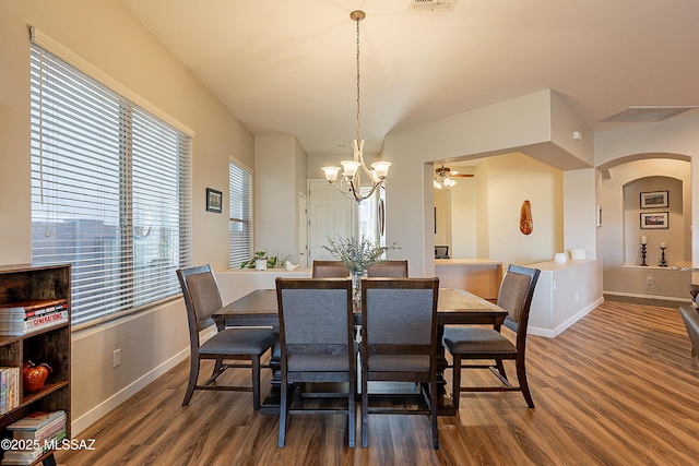 dining room with dark hardwood / wood-style flooring and ceiling fan with notable chandelier