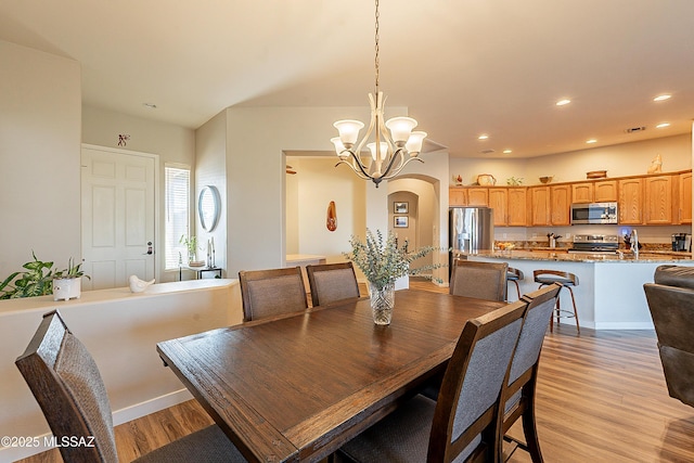 dining space with light hardwood / wood-style flooring and an inviting chandelier