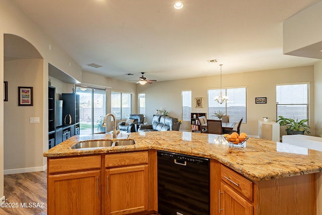 kitchen featuring sink, black dishwasher, an island with sink, and decorative light fixtures