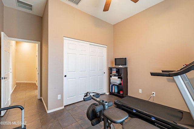 workout area with dark tile patterned floors and ceiling fan