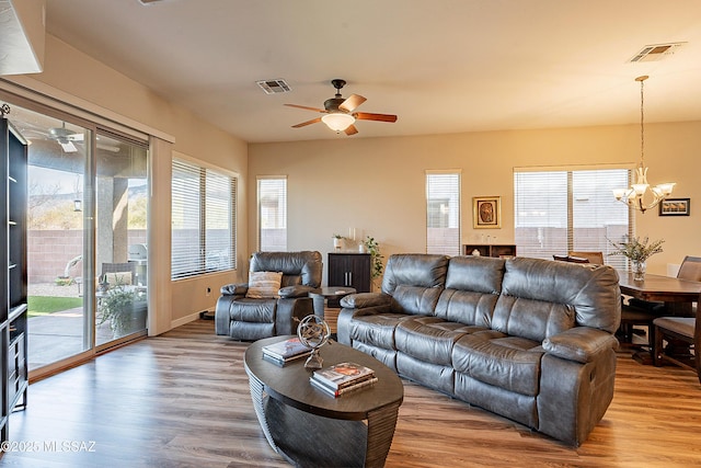 living room with ceiling fan with notable chandelier and hardwood / wood-style floors