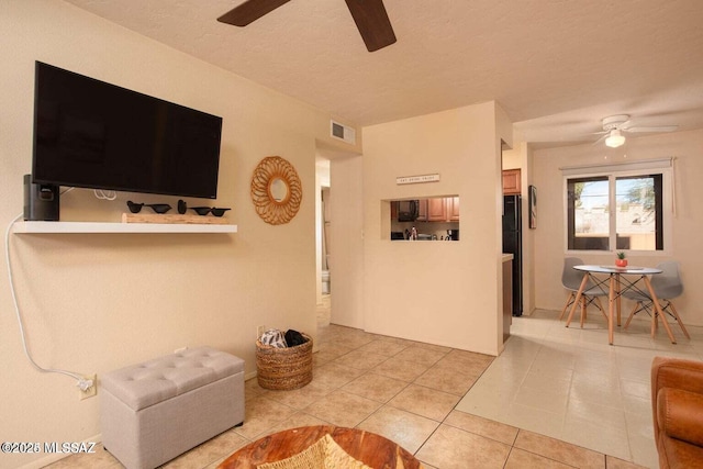 living room featuring light tile patterned floors, a textured ceiling, and ceiling fan