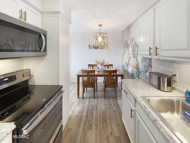 kitchen featuring sink, light hardwood / wood-style flooring, appliances with stainless steel finishes, tasteful backsplash, and white cabinets