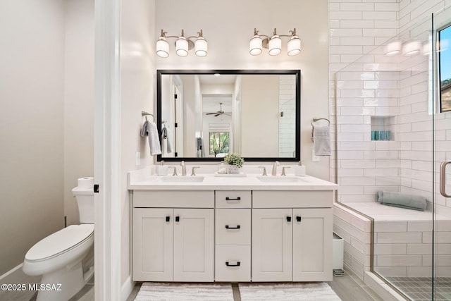 bathroom with an enclosed shower, vanity, toilet, and ceiling fan