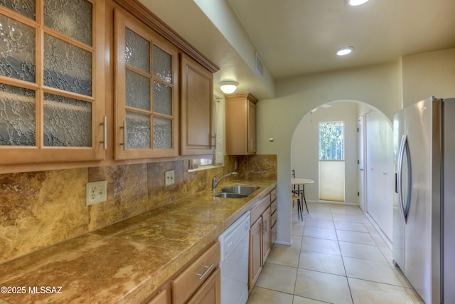 kitchen with sink, light tile patterned floors, stainless steel fridge, white dishwasher, and decorative backsplash