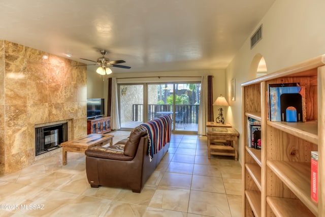 tiled living room featuring a tiled fireplace and ceiling fan