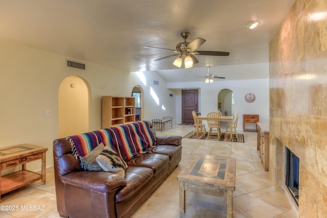 living room featuring light tile patterned floors, a tile fireplace, and ceiling fan