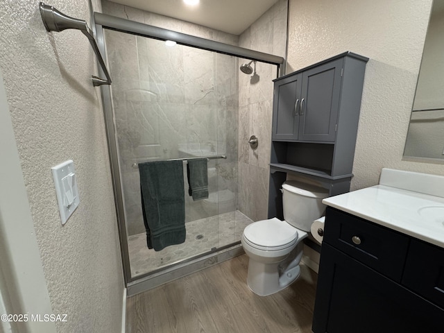 bathroom featuring vanity, hardwood / wood-style floors, a shower with door, and toilet