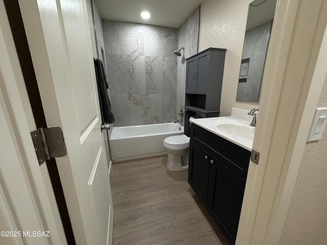 full bathroom with tiled shower / bath, vanity, toilet, and hardwood / wood-style floors