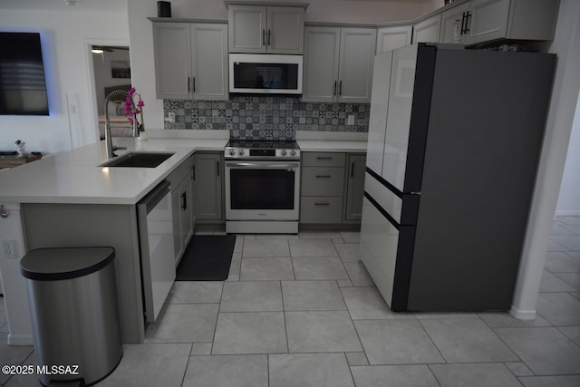 kitchen with stainless steel appliances, sink, decorative backsplash, and gray cabinets