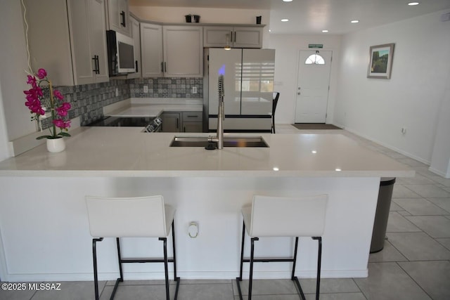 kitchen with white refrigerator, kitchen peninsula, a breakfast bar area, and gray cabinetry