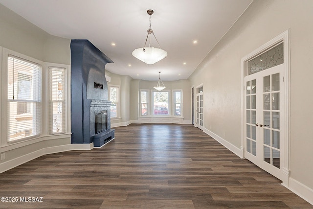 unfurnished living room featuring dark hardwood / wood-style floors, a fireplace, and french doors