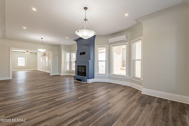 unfurnished living room featuring dark hardwood / wood-style flooring, a wall mounted air conditioner, and a large fireplace