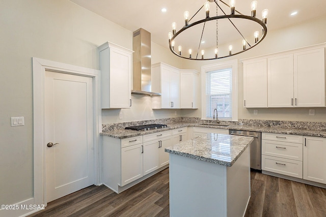 kitchen with white cabinetry, stainless steel appliances, decorative light fixtures, and wall chimney range hood