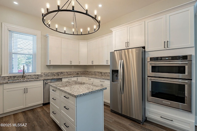 kitchen with sink, hanging light fixtures, stainless steel appliances, light stone countertops, and white cabinets