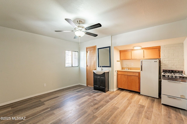 kitchen with ceiling fan, sink, white appliances, and light wood-type flooring