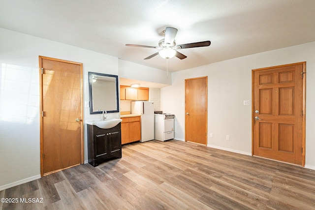 kitchen with ceiling fan, sink, white appliances, and light hardwood / wood-style floors