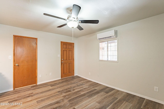 unfurnished room with ceiling fan, a wall mounted AC, and hardwood / wood-style floors