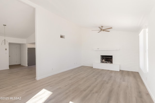 unfurnished living room featuring ceiling fan, lofted ceiling, a fireplace, and light hardwood / wood-style flooring