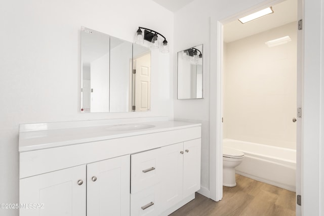 full bathroom featuring washtub / shower combination, wood-type flooring, toilet, and vanity