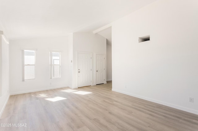 empty room with lofted ceiling and light hardwood / wood-style floors