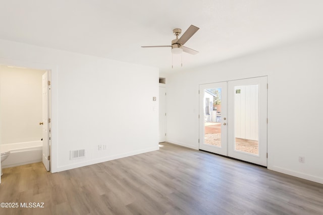 empty room featuring light hardwood / wood-style flooring, ceiling fan, and french doors