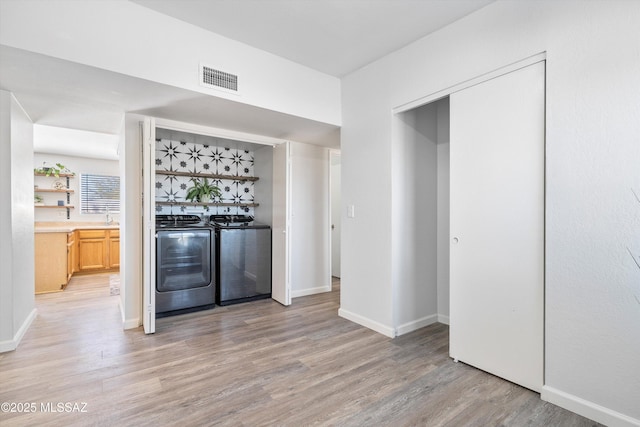 bar with light brown cabinetry, washing machine and clothes dryer, and light wood-type flooring