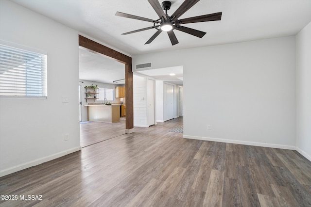 unfurnished living room featuring dark wood-type flooring, ceiling fan, and vaulted ceiling