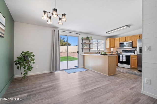 kitchen featuring hanging light fixtures, stainless steel appliances, a notable chandelier, light hardwood / wood-style floors, and kitchen peninsula