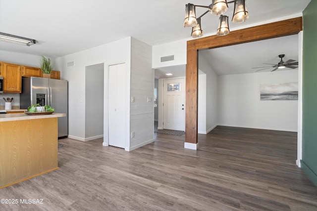 kitchen with appliances with stainless steel finishes, dark hardwood / wood-style floors, ceiling fan with notable chandelier, pendant lighting, and lofted ceiling