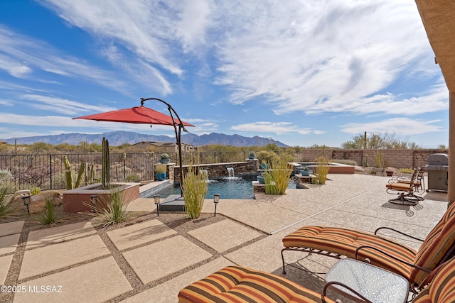 view of patio with a fenced in pool, a mountain view, and pool water feature