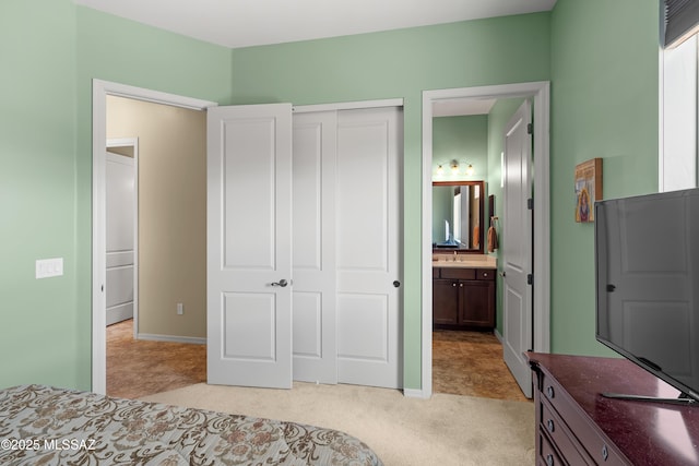 carpeted bedroom with sink, ensuite bath, and a closet