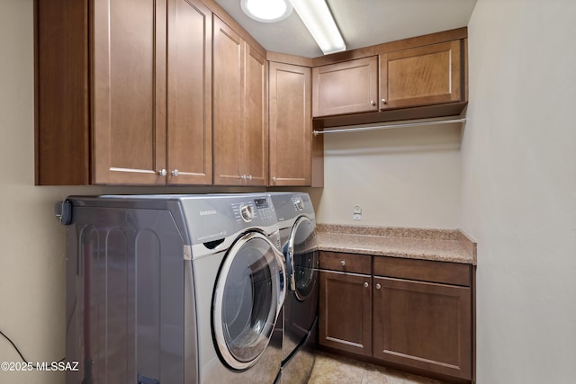 clothes washing area featuring cabinets and washer and dryer