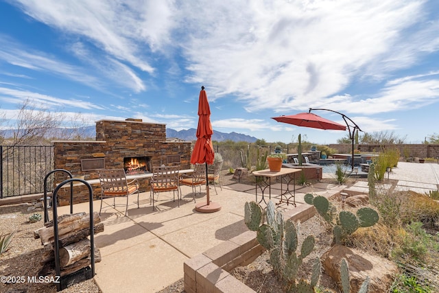 view of patio / terrace featuring a mountain view, a swimming pool, and an outdoor stone fireplace