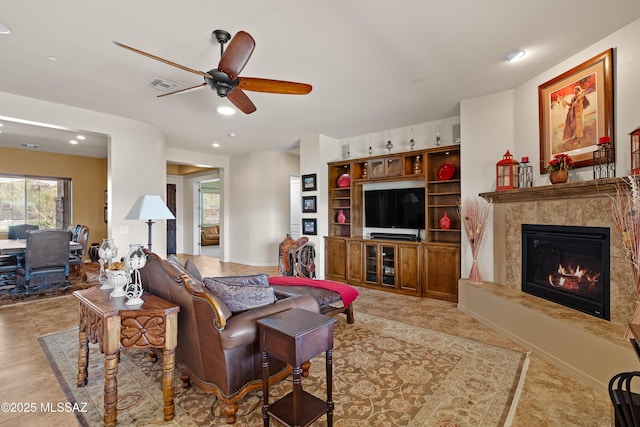 tiled living room with a premium fireplace and ceiling fan