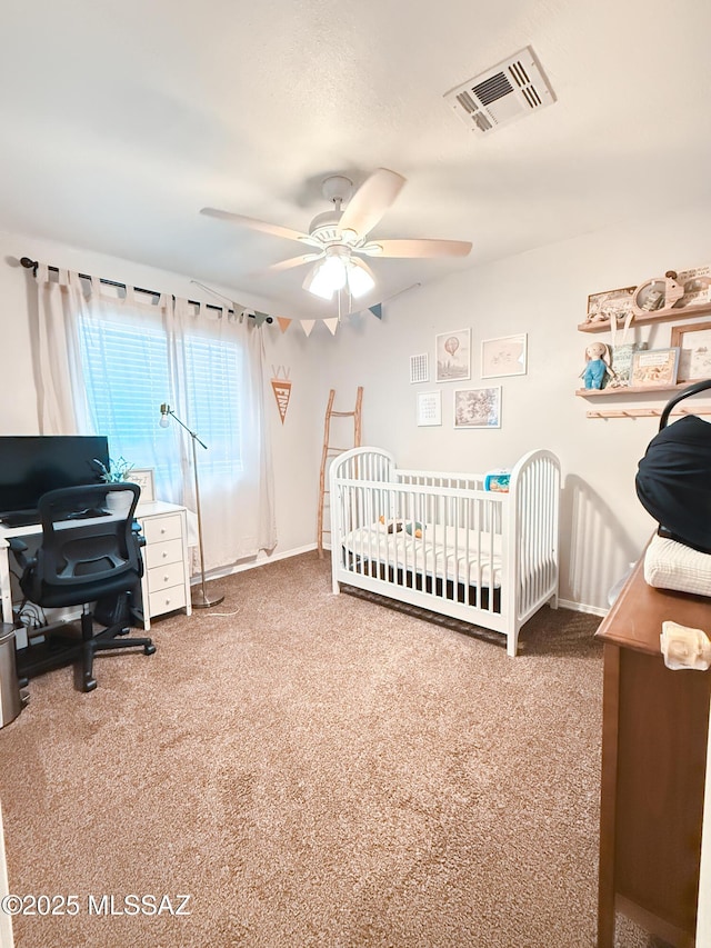 carpeted bedroom featuring a crib and ceiling fan