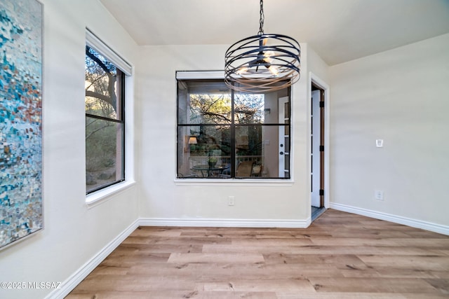 unfurnished dining area with a chandelier and light hardwood / wood-style flooring