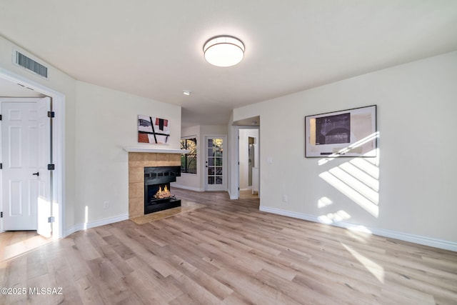 unfurnished living room featuring a tile fireplace and light wood-type flooring