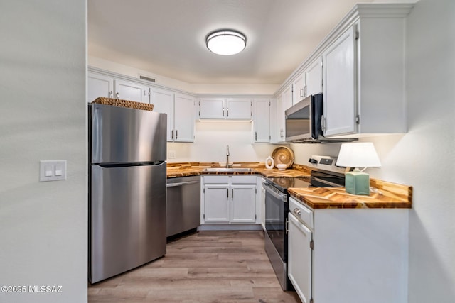 kitchen featuring sink, light hardwood / wood-style flooring, white cabinets, and appliances with stainless steel finishes