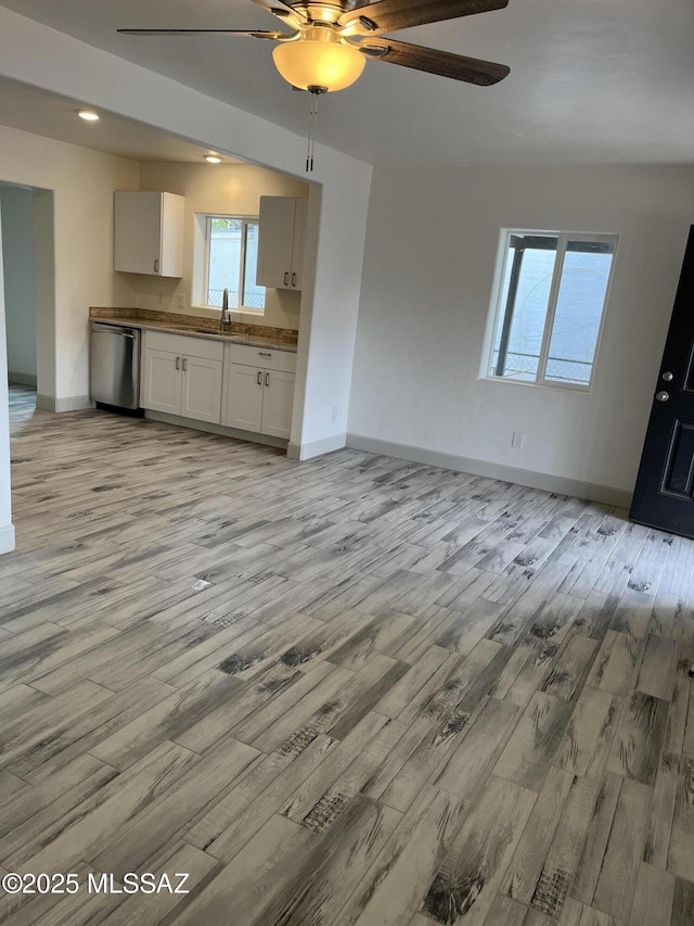 unfurnished living room featuring ceiling fan, sink, and light wood-type flooring