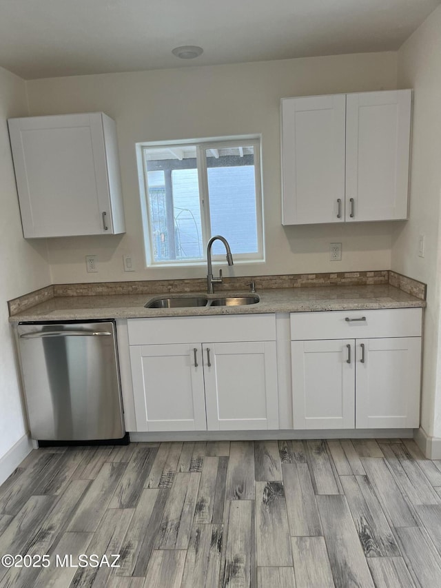 kitchen featuring dishwasher, sink, white cabinets, and light hardwood / wood-style flooring