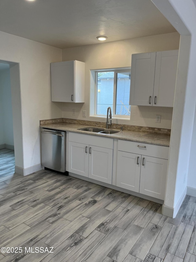 kitchen featuring sink, stainless steel dishwasher, white cabinets, and light wood-type flooring