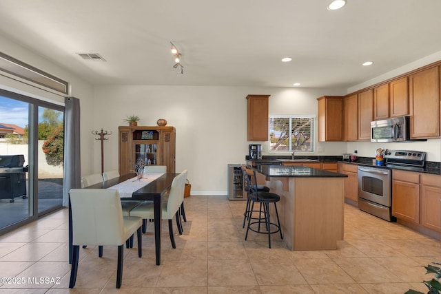 kitchen with wine cooler, sink, a kitchen breakfast bar, a kitchen island, and stainless steel appliances