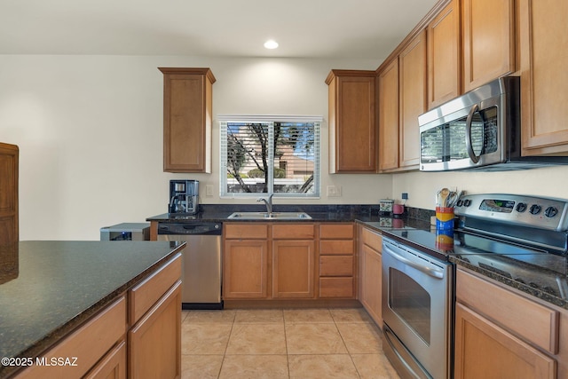 kitchen with appliances with stainless steel finishes, sink, light tile patterned floors, and dark stone counters