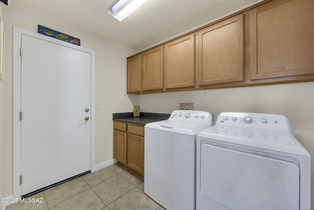 laundry room with washer and dryer, light tile patterned floors, and cabinets