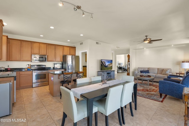 kitchen with stainless steel appliances, a center island, light tile patterned floors, and ceiling fan